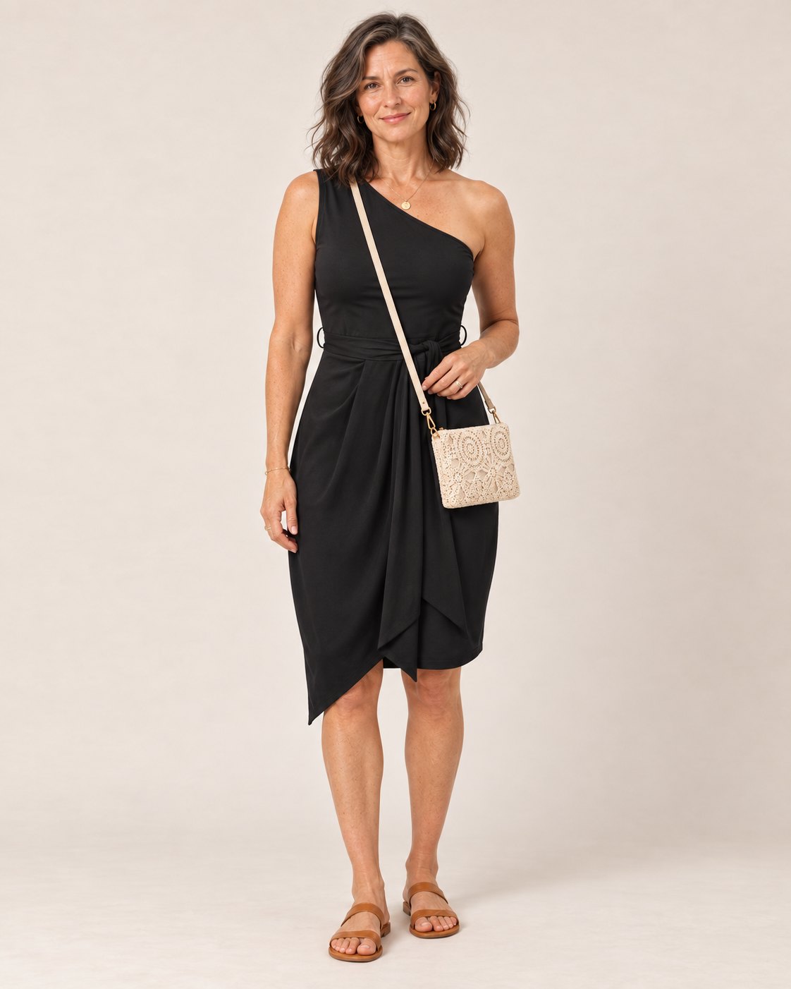Woman wearing the black one-shoulder Sofia Dress with the cream floral lace crochet crossbody bag